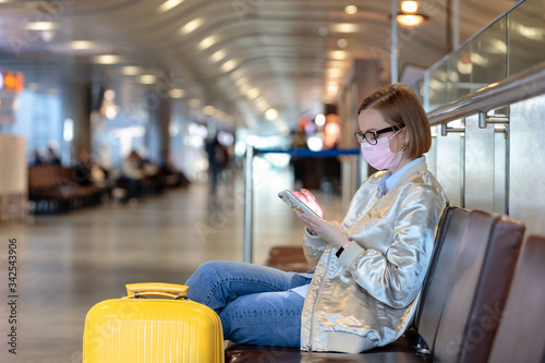 Fotomural Woman upset over flight cancellation, writes message to family, sitting in almost empty airport terminal due to coronavirus pandemic/Covid-19 outbreak travel restrictions, collapse