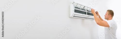 Fotografía Portrait Of A Young Man Adjusting Air Conditioning System