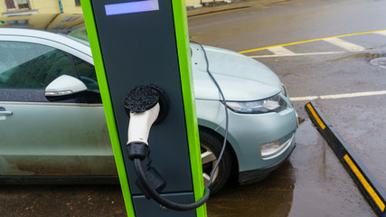 Electric car on charching station plugged. Ecological and recharging concept.