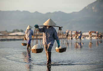 Salt and Silhoutte of salt farmer on salt field Hon Khoi, Nha Trang, Khanh Hoa, Vietnam.