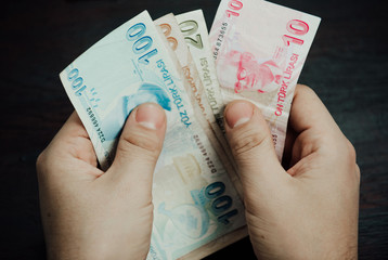 Many hundred Turkish lira on wooden table background texture. bundles of money scattered on the office desk. wealth and income concept. Counting money. 