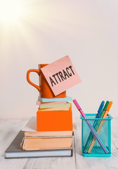 Poster - Writing note showing Attract. Business concept for to draw by a physical force causing or tending to cause to approach Cup stacked note pad books on square box pens metal holder wooden table
