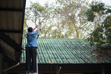 Low Angle View Of Man Repairing Satellite Dish On Roof
