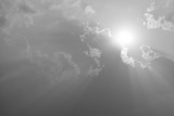 Fototapeta Lawenda - A black and white image of a large cloud covering the sun shining.