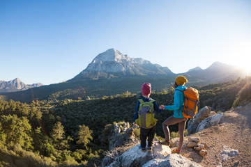 The boy and his mother are standing on the top of the mountain.