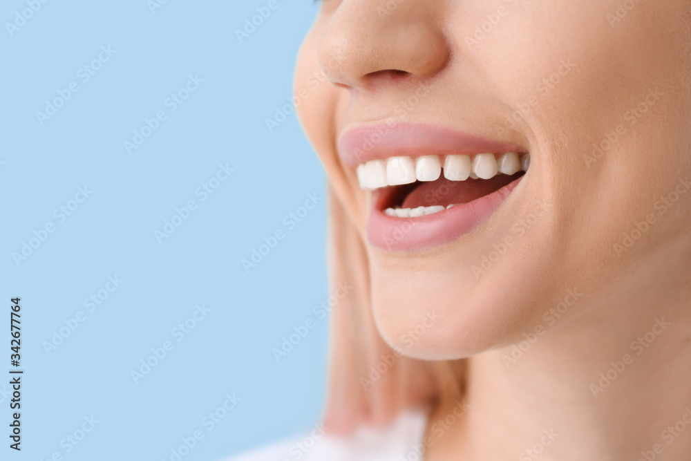Young woman with healthy teeth on color background, closeup