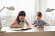 © Максим Корабельщиков - Two small children do their homework at home.