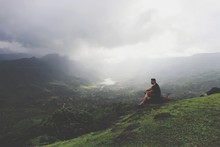 Man Sitting On Mountain Against Sky