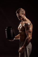 Wall Mural - Sport backgrounds. Strong bodybuilder holding a plastic jar with a dry protein Isolated. Sport food.