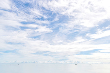 cloudy white sky and white sea with little black spots of fisherman ships