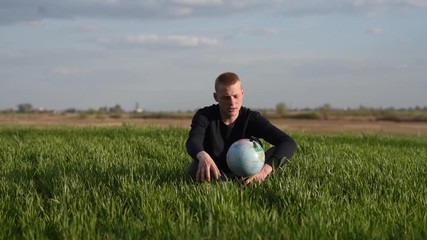 
man exploring earth globe while sitting in green field