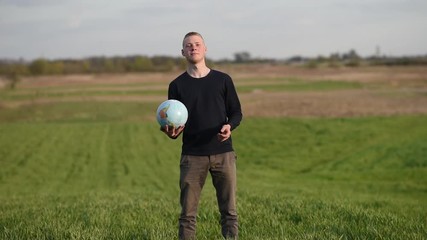 man throws earth globe in green field