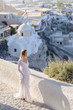 © wolfhound911 - Beautiful bride In a white dress posing against the backdrop of the city of Thira, Santorini.