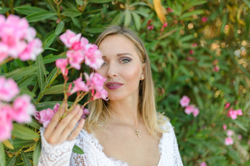 Wall Mural - Portrait of a beautiful bride in a white dress in a bush of flowers.