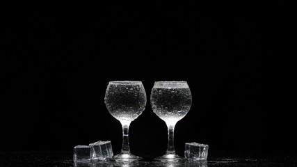 Two frozen vodka shot glasses with ice. Black background