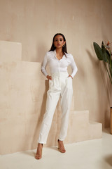 Wall Mural - Beautiful sexy brunette woman tanned skin face cosmetic makeup wear white suit pants for date walk office fashion clothes style collection interior room sand color safari summer casual.