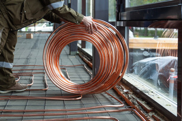 Wall Mural - Plumber laying copper pipes on floor with warm heating