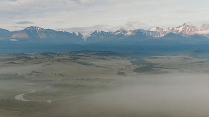 Wall Mural - foggy morning in mountain valley, rock ridge on horizon in clouds and haze