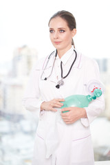 Portrait of a young female doctor with a stethoscope on a white background, she looks away    