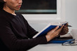 © Touchr - Young man reading book at work desk late at night, Knowledge and learning concept.