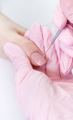 Woman in nail salon receiving manicure by beautician. Manicure process in beauty salon, close up. Close up of a woman hand with pink nail polish after the manicure.