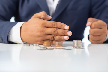 Businessman hand with putting money coins a desk in the office
concept: Saving money wealth and financial Personal, finance management  loan for a home,
 diagram chart earnings to plan profit
