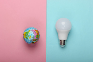 Eco concept. LED light bulb and globe on a blue-pink pastel background. Top view.