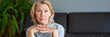 © JENOCHE - middle-aged blond woman sitting on a sofa at home