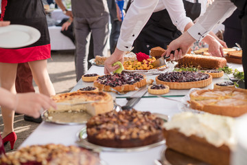 cake buffet with waiters serving and festivepeople taking their parts on the outside, might be on a wedding