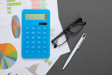 Wall Mural - Analysis of statistics. Economic calculation. Calculator, glasses, graphs and charts on gray background. Top view. Flat lay