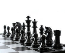 Black Chess Pieces On The Chessboard On White Background. Closeup Of Some Chess Figures. Copy Space