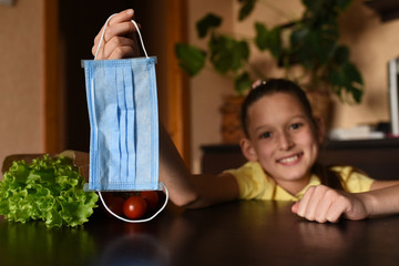 little girl with laptop. young woman holding blank sign. Coronavirus. Woman with face mask on quarantine, cooks in the kitchen at home during coronavirus crisis. Stay at home. Enjoy cooking at home. F