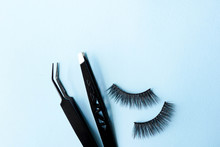 High Angle View Of False Eyelashes With Tweezers On Blue Background