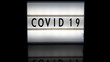 Covid 19 letters on a light box on reflective surface