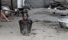 African Child Cools Down In A Bucket Of Water During A Hot Afternoon. Photo From A Fishing Village Ada Foah Ghana West Africa.