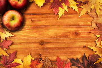 Wall Mural - Apples and maple leaves disposed on a wooden table. Flat lay, top view of autumn decoration concept.