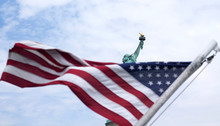 Low Angle View Of American Flag With Statue Of Liberty In Background