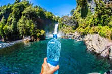 Optical Illusion Of Person Holding Waterfall In Bottle