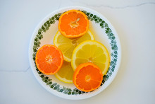 Orange And Lemon Slices On A Saucer Set On White Marble