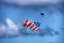 Person Paragliding With American Flag In Sky