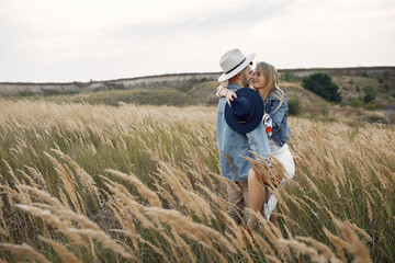 Loving couple in a wheat field. Beautiful blonde in a blue hat.