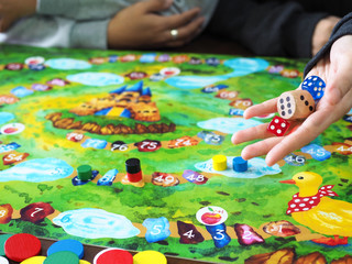 Two people playing children board game at home.  Family activity with selective focus. 