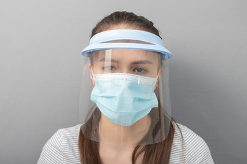 Poster - Coronavirus Remedy Young woman in a protective mask screen with a visor on a gray background