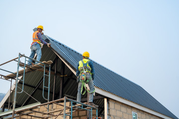 Poster - Roofer using air or pneumatic nail gun and installing metal roof tile on top roof,Builder Working On Roof Of new building.