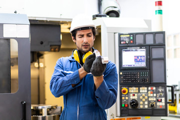 Mechanical Engineering control lathe machine and quality check in factory facility. Safety First at work place. Man Worker at industrial factory wearing uniform and hardhats.