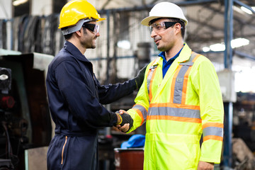 Two man Worker hand shake at industrial factory wearing uniform and hard hats and Mechanical repair.  Engineer Operating  lathe Machinery