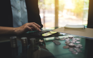 Wall Mural - businesswoman calculating with coins stack on the table for saving money and financial concept