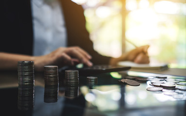 Wall Mural - businesswoman calculating with coins stack on the table for saving money and financial concept