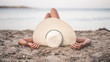 Young woman relaxing on the Mallorca beach , on the sand, watching the sea with her nice big creamy coloured hat. Woman taking the rest on the sunny summer holidays enjoying beautiful weather.