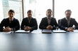 © fizkes - Four serious confident businessmen sitting at table in boardroom, looking at camera, focused hr managers listening to candidate, making decision, business partners gathering at corporate meeting